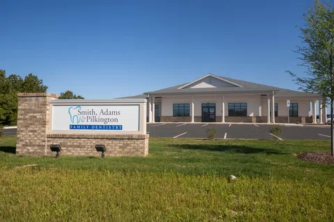 Front view of Smith Adams Pilkington Family Dentistry building and sign under clear blue sky.