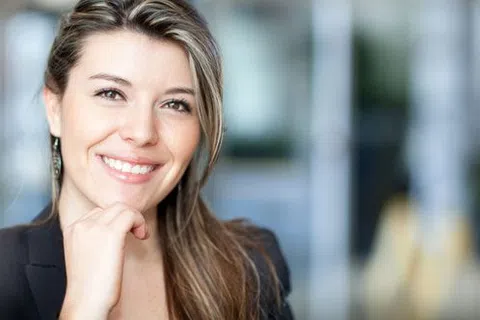 Smiling professional woman with long hair wearing business attire in a bright office environment