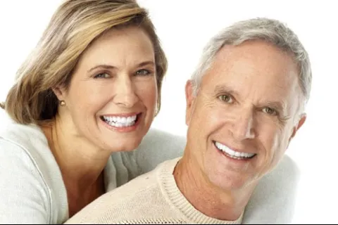 Happy middle-aged couple smiling with bright white teeth in a close-up portrait on white background