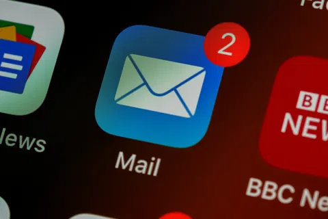 Mail app icon with two unread messages notification on a smartphone screen among other app icons.