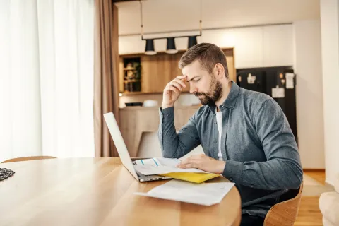 a man sitting at a table with a laptop and papers