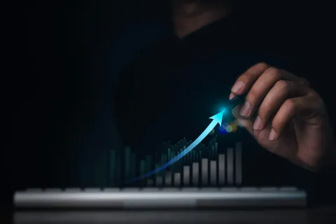 Hand drawing a glowing upward arrow over a rising bar chart symbolizing business growth and success.