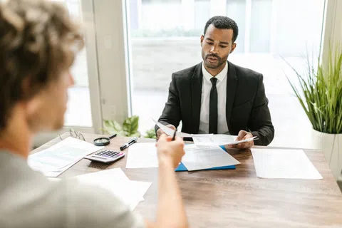 Professional man in a suit reviewing documents during a business meeting with a colleague.