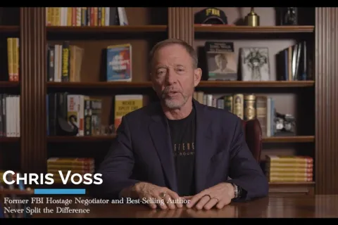 Chris Voss speaking in an office setting with bookshelves, identified as former FBI negotiator and author.