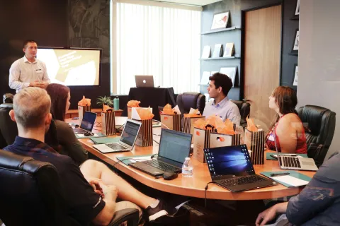 Business team attends a presentation in a modern conference room with laptops and gift bags on the table