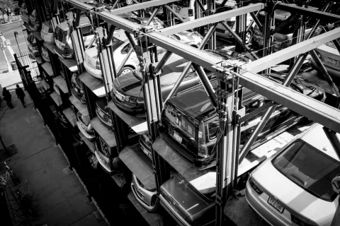 Black and white image of automated multi-level car parking system in urban area with several parked cars.