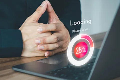 Person with clasped hands next to laptop showing a 25% loading progress graphic and Please Wait text.
