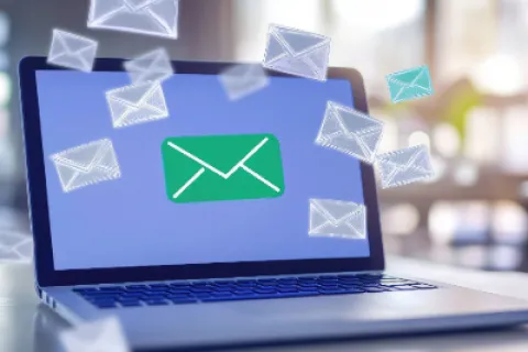 Laptop screen showing a green email icon with multiple floating envelope symbols representing email messages.