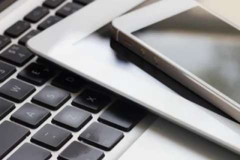 Smartphone and tablet stacked on a laptop keyboard showcasing modern digital devices for work and communication