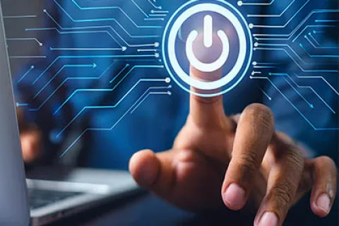 Finger pressing digital power button icon with technology circuit connections and laptop in background