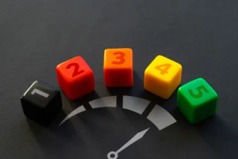 Colorful numbered dice from 1 to 5 arranged in an arc over a gauge graphic indicating increasing levels.