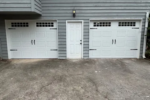 Gray house exterior with white double garage doors and a central white door on a concrete driveway.