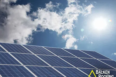 Solar panels angled under a bright sun with blue sky and scattered clouds, promoting renewable energy.