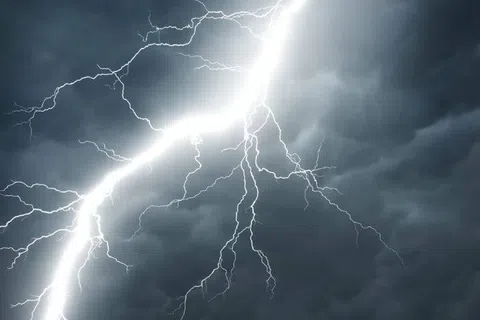 Bright lightning bolt striking through dark, stormy clouds against a gloomy sky, capturing a powerful thunderstorm moment.