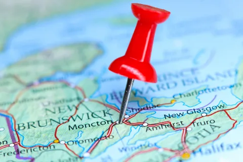 Red pushpin marking Moncton on a detailed map of New Brunswick and surrounding areas.