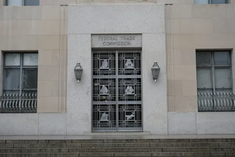Entrance to the Federal Trade Commission building with decorative metal doors and stone facade.