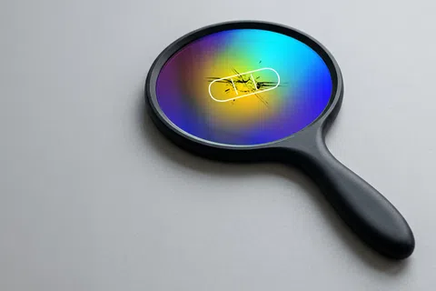 Black handheld magnifier with a cracked rainbow-colored lens and a white bandage on the surface.