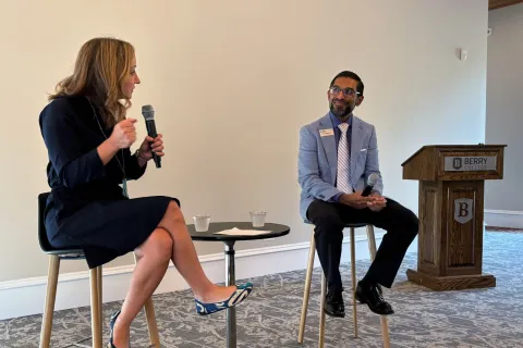 Two professionals sitting on high stools holding microphones during a discussion at Berry College event.
