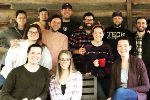 Group of Berry alums pose together outside a log cabin