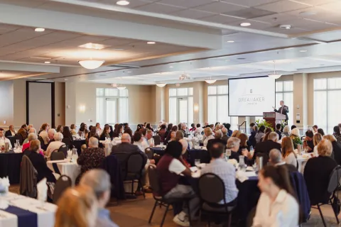 A well-attended conference event with a speaker and engaged audience in a spacious venue.