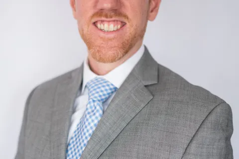 a man wearing a suit and tie smiling at the camera