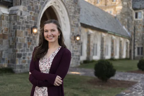 Girl in Purple Sweater Standing in Front of Stone Building