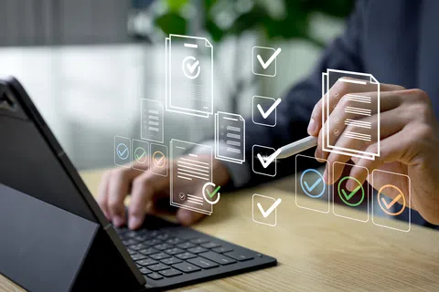 Businessperson using tablet and stylus with digital checklists and documents floating in workspace.