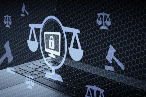 Laptop keyboard with digital icons of computer security, scales of justice, and a gavel representing cyber law.