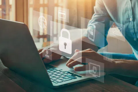 Person typing on laptop with digital padlock and security icons overlay symbolizing cybersecurity and data protection.