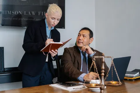 Two lawyers discussing case notes in a law office with legal scales and laptop on the desk