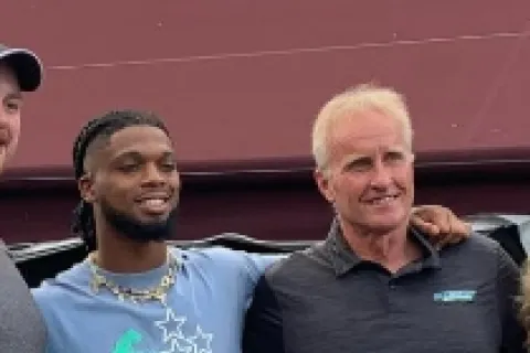 a person with the arm around another man smiling