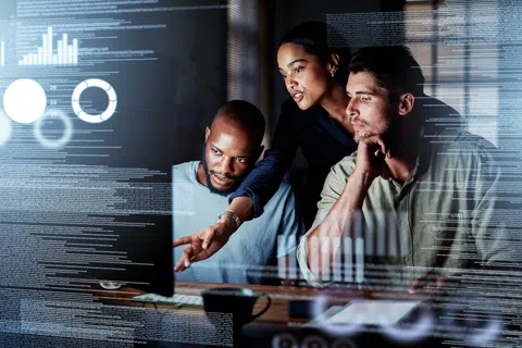 Three professionals analyzing data and charts on a large transparent screen in a modern office setting
