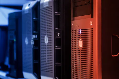 Row of black computer servers with glowing indicator lights in a data center environment
