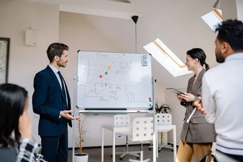 Business team discussing growth plans with charts on whiteboard in modern office with natural light.