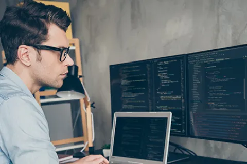 a man sitting at a desk with a computer and a monitor