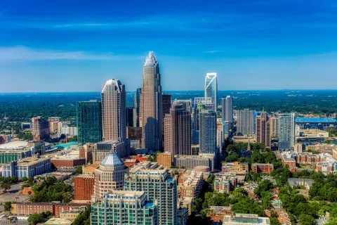 Aerial view of a modern city skyline with tall skyscrapers, dense buildings, and clear blue sky.