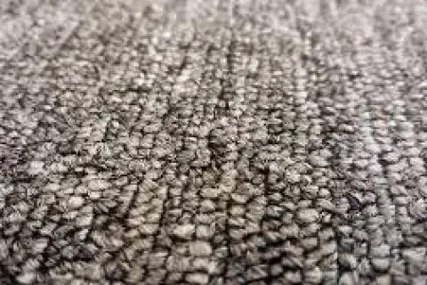 Close-up of gray textured carpet fibers showing detailed woven pattern and texture in soft lighting