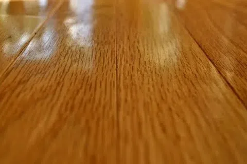Close-up of shiny polished wooden floorboards with natural grain texture and warm brown tones