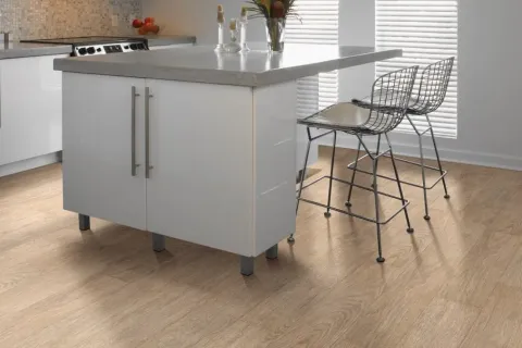 Modern kitchen island with gray countertop, white cabinets, and two metal wire bar stools on wood floor.