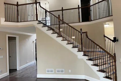 Interior of a home featuring a wooden staircase with black iron balusters and hardwood flooring.