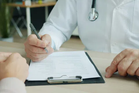 Doctor in white coat filling out a medical form on clipboard during a HIPAA compliance audit
