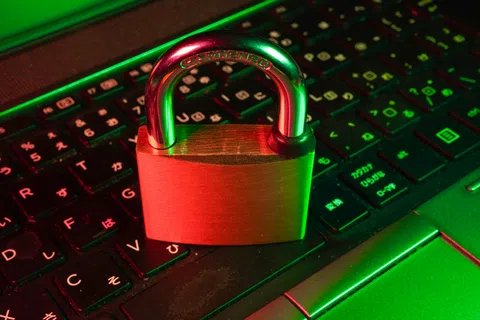 Padlock placed on a laptop keyboard illuminated with red and green lighting symbolizing cybersecurity and data protection.