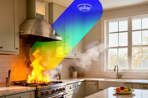 Kitchen stove fire with flames and smoke near white cabinets and window in modern home kitchen