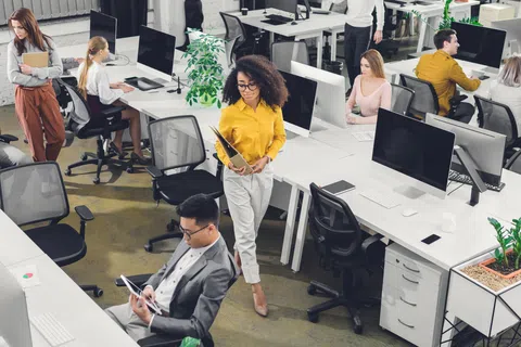 Modern open office with diverse young professionals working on computers and collaborating throughout the space
