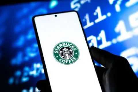 Smartphone screen displaying Starbucks Coffee logo held by hand with blurred blue digital background.
