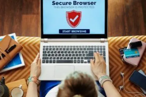 Person using laptop displaying secure browser with shield icon and start browsing button on screen