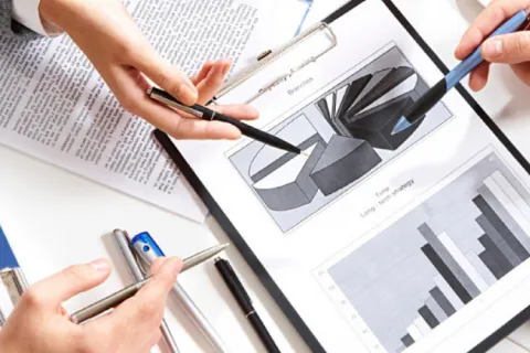 Business team analyzing pie and bar charts with coffee cups on desk during meeting