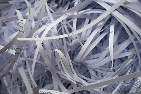 Close-up of tangled shredded paper strips with printed text under bright light