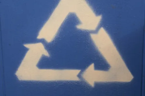 White recycling symbol with three arrows forming a triangle on a blue textured background.
