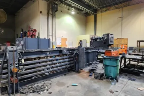 Industrial workshop with large metal machinery, equipment, and tools in a spacious warehouse setting.